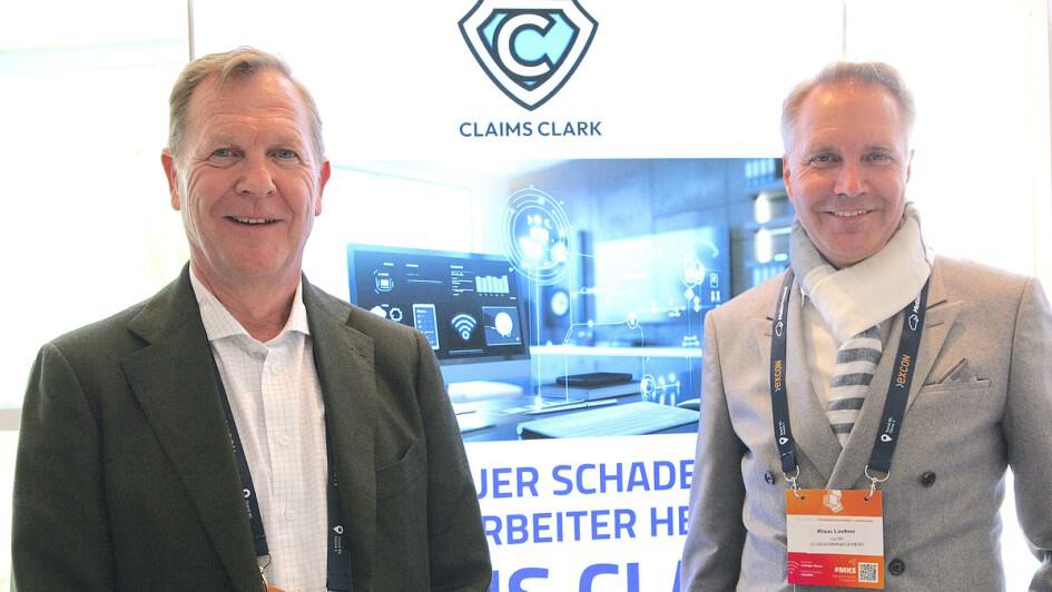 Zwei Männer bei Claims Clark Konferenz mit Logo im Hintergrund.